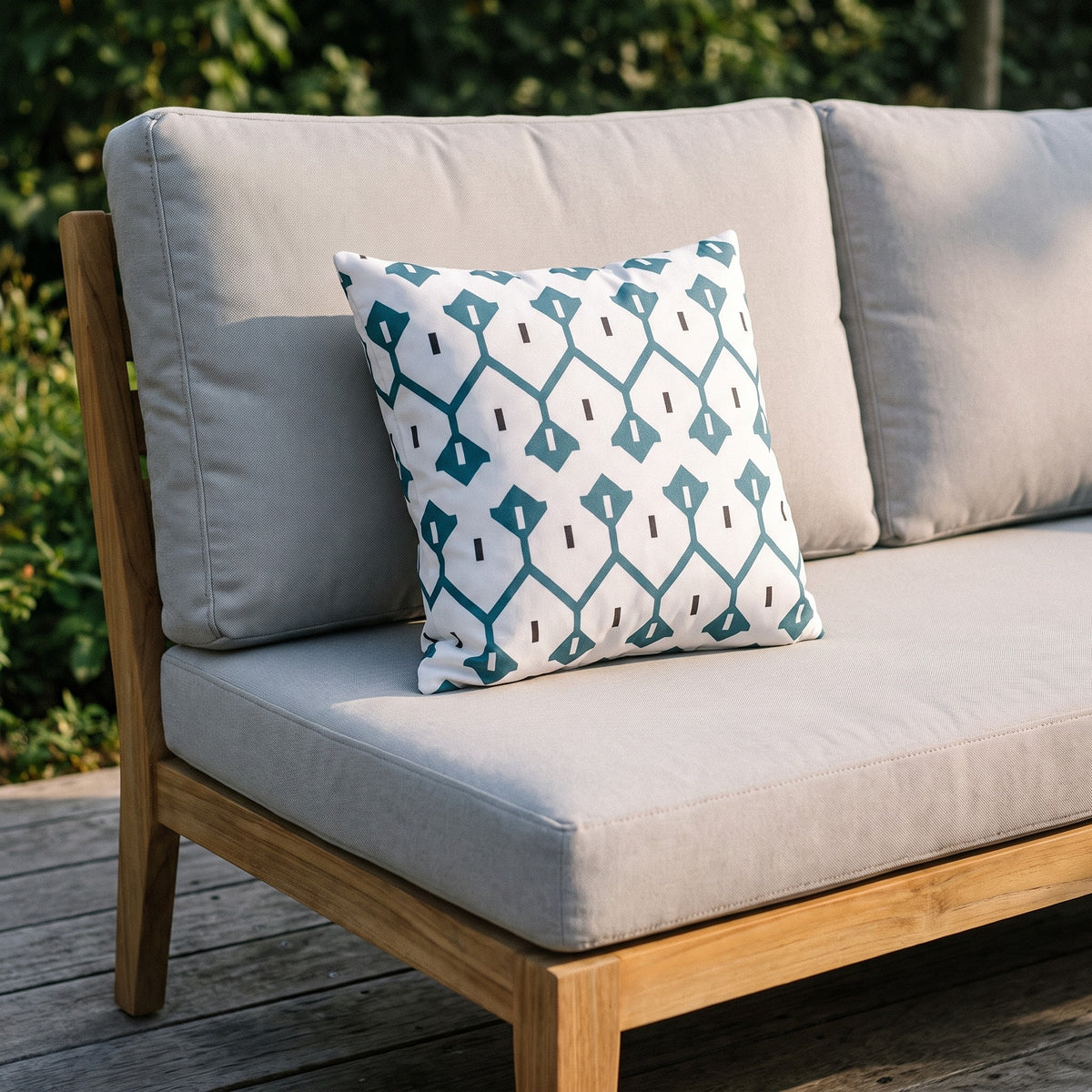 Housse de coussin extérieur imperméable motif Treillis bleu canard sur un canapé de jardin en teck, terrasse ensoleillée