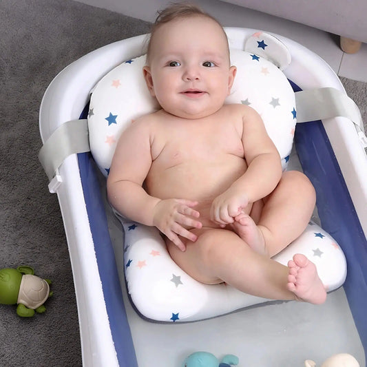 Bébé allongé sur un coussin de bain à étoiles, installé dans une baignoire bébé blanche et bleu marine