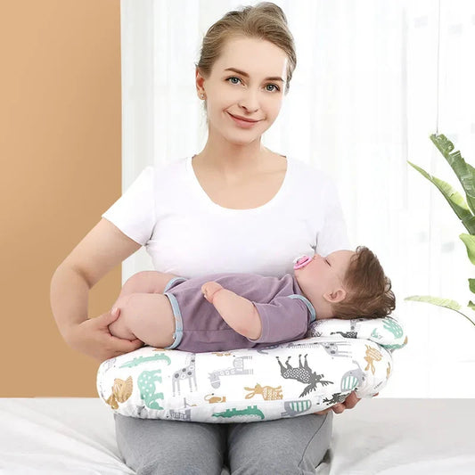 Maman assise sur un lit, bébé allongé sur un coussin d'allaitement à motif animaux posé autour de sa taille