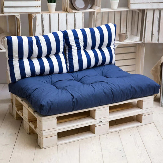 Canapé en palettes blanchies avec un coussin d'assise bleu marine capitonné et deux coussins de dossier rayés bleu et blanc