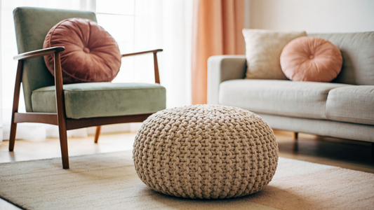 Salon lumineux avec des coussins ronds : un grand coussin en velours sur un fauteuil, un pouf tricoté au sol et de petits coussins sur le canapé
