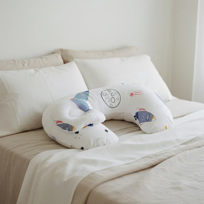 Coussin d'allaitement motif espace posé sur un lit