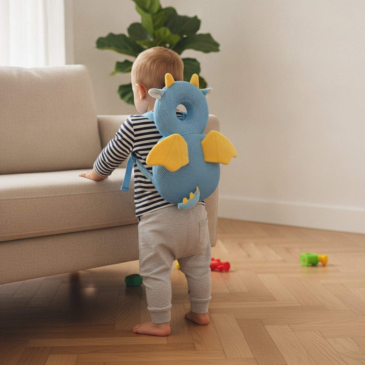 Bébé debout contre le canapé avec le coussin anti-chute Dragon sur le dos