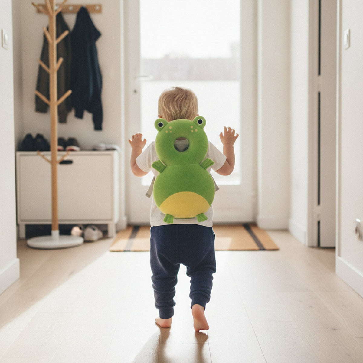 Bambin qui fait ses premiers pas avec le coussin anti-chute Grenouille sur le dos