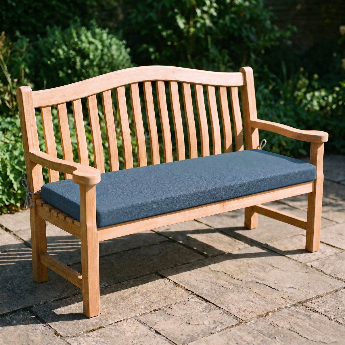 Coussin de banquette sur mesure en polyester coloris bleu pétrole, coussin plat avec cordons d'attache, posé sur un banc de jardin en teck