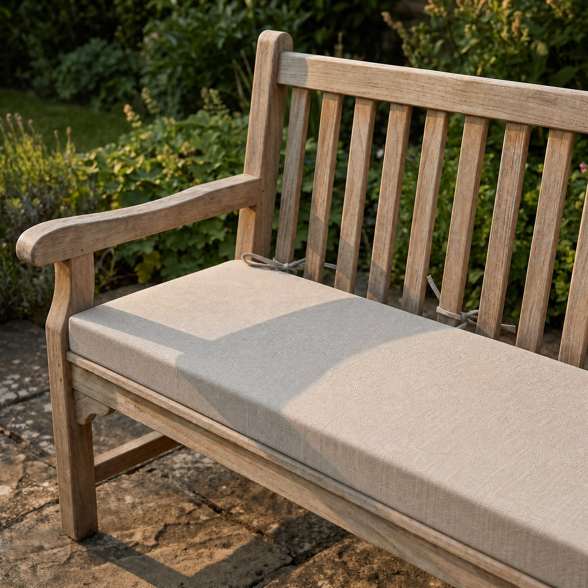 Coussin de banquette sur mesure en polyester coloris grège, coussin plat avec cordons d'attache, posé sur un banc de jardin en teck
