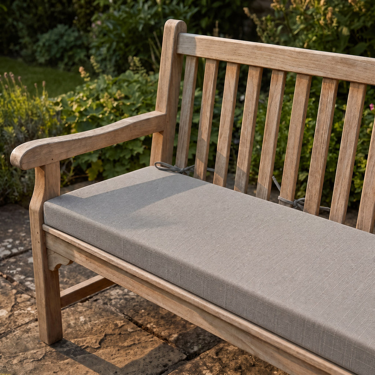 Coussin de banquette sur mesure en polyester coloris gris, coussin plat avec cordons d'attache, posé sur un banc de jardin en teck