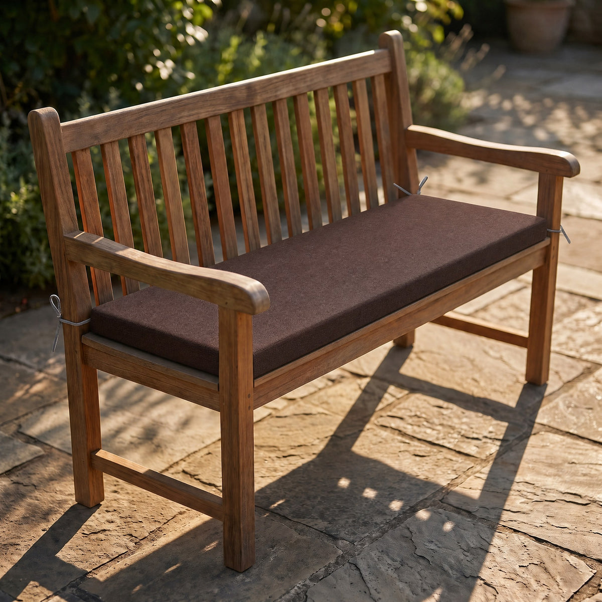 Coussin de banquette sur mesure en polyester coloris marron, coussin plat avec cordons d'attache, posé sur un banc de jardin en teck