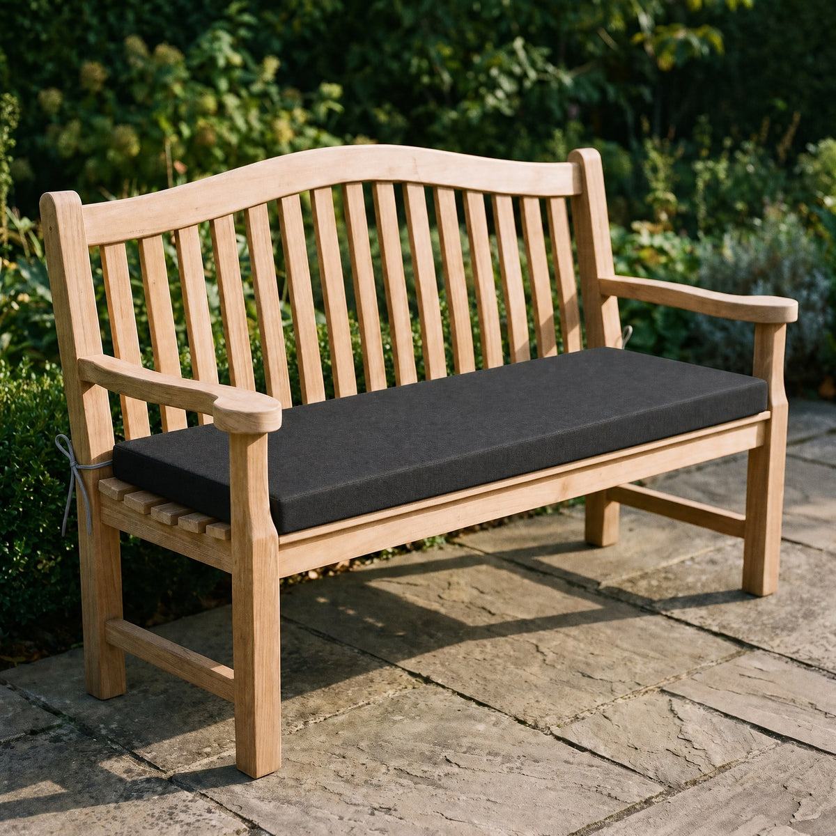 Coussin de banquette sur mesure en polyester coloris noir, coussin plat avec cordons d'attache, posé sur un banc de jardin en teck