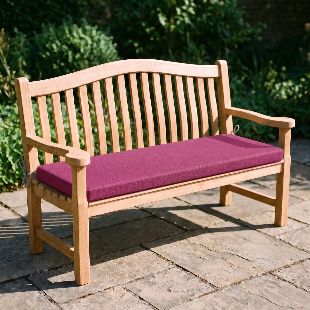 Coussin de banquette sur mesure en polyester coloris rose fuchsia, coussin plat avec cordons d'attache, posé sur un banc de jardin en teck