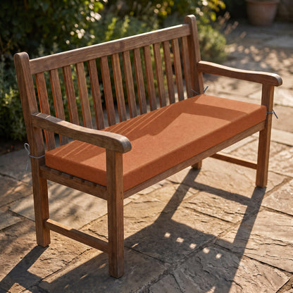 Coussin de banquette sur mesure en polyester coloris terracotta, coussin plat avec cordons d'attache, posé sur un banc de jardin en teck