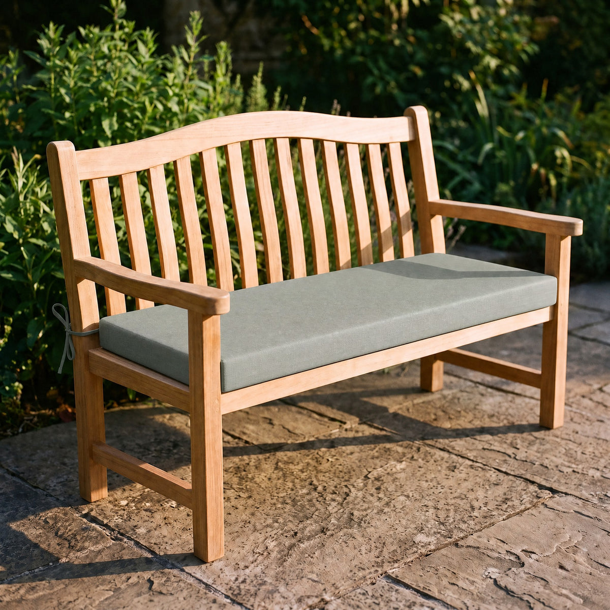 Coussin de banquette sur mesure en polyester coloris vert, coussin plat avec cordons d'attache, posé sur un banc de jardin en teck