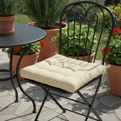 Coussin beige sur une chaise bistrot en fer forgé noir, en terrasse
