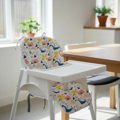 Coussin de chaise haute motif dinosaures installé sur une chaise haute en bois blanc