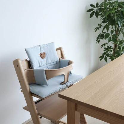 Coussin de chaise haute évolutive bleu, assise et dossier, sur une chaise en bois près de la table