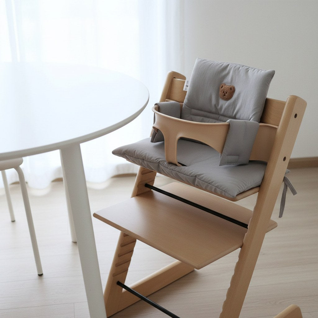 Coussin de chaise haute évolutive gris installé sur une chaise en bois, dans une salle à manger lumineuse