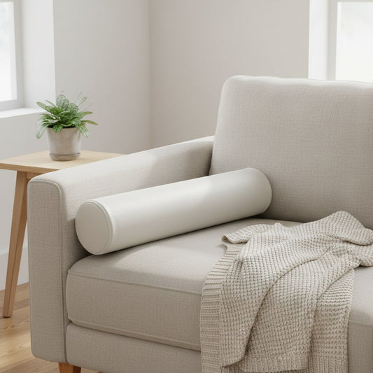Coussin cylindrique en cuir blanc cassé posé au bout d'un canapé en lin beige