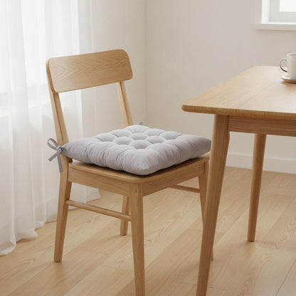 Coussin de chaise 40 x 40 cm gris clair noué sur une chaise en chêne dans une cuisine lumineuse