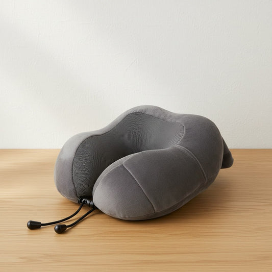 Coussin de voyage gris en forme de U avec cordon de serrage, posé sur une table en chêne clair