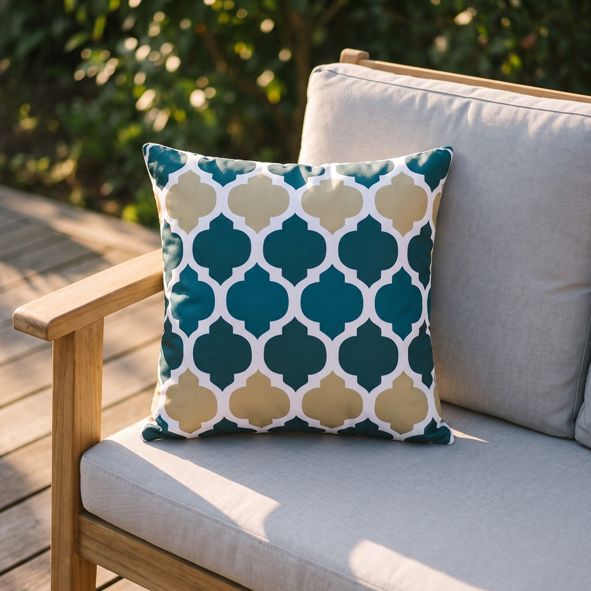 Housse de coussin extérieur imperméable motif Arabesque bleu et jaune sur un canapé de jardin en teck, terrasse ensoleillée