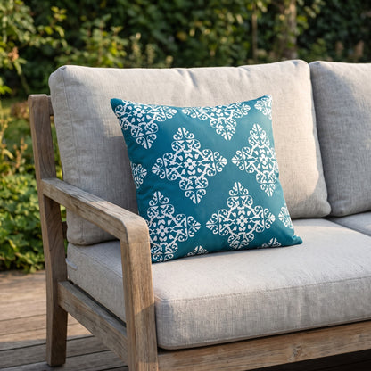 Housse de coussin extérieur imperméable motif Médaillon bleu canard sur un canapé de jardin en teck, terrasse ensoleillée