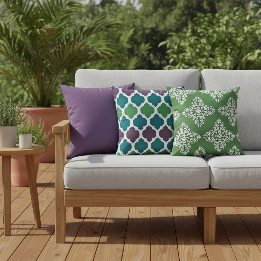 Housses de coussin extérieur imperméables motifs Uni violet, Arabesque vert et violet et Médaillon vert sur un canapé de jardin en teck, terrasse ensoleillée