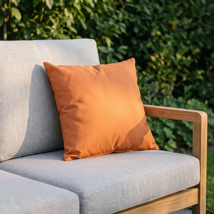 Housse de coussin extérieur imperméable motif Uni orange sur un canapé de jardin en teck, terrasse ensoleillée