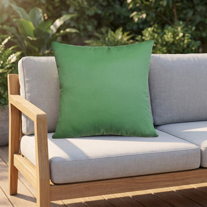Housse de coussin extérieur imperméable motif Uni vert sur un canapé de jardin en teck, terrasse ensoleillée