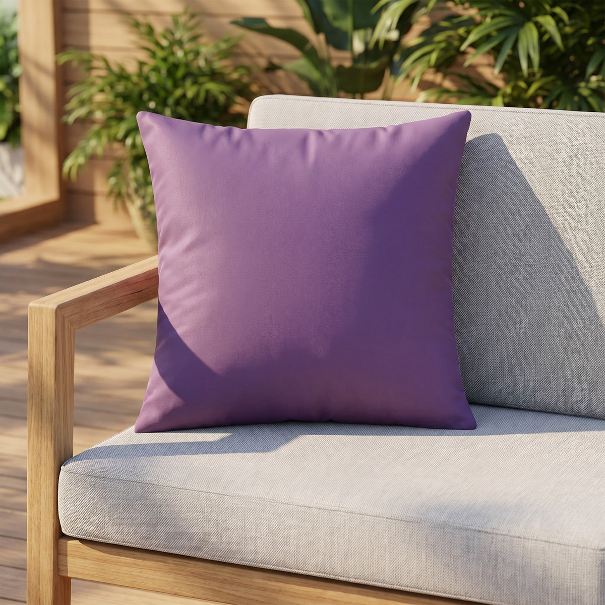 Housse de coussin extérieur imperméable motif Uni violet sur un canapé de jardin en teck, terrasse ensoleillée