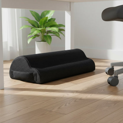 Coussin repose-pieds noir en mousse posé sous un bureau