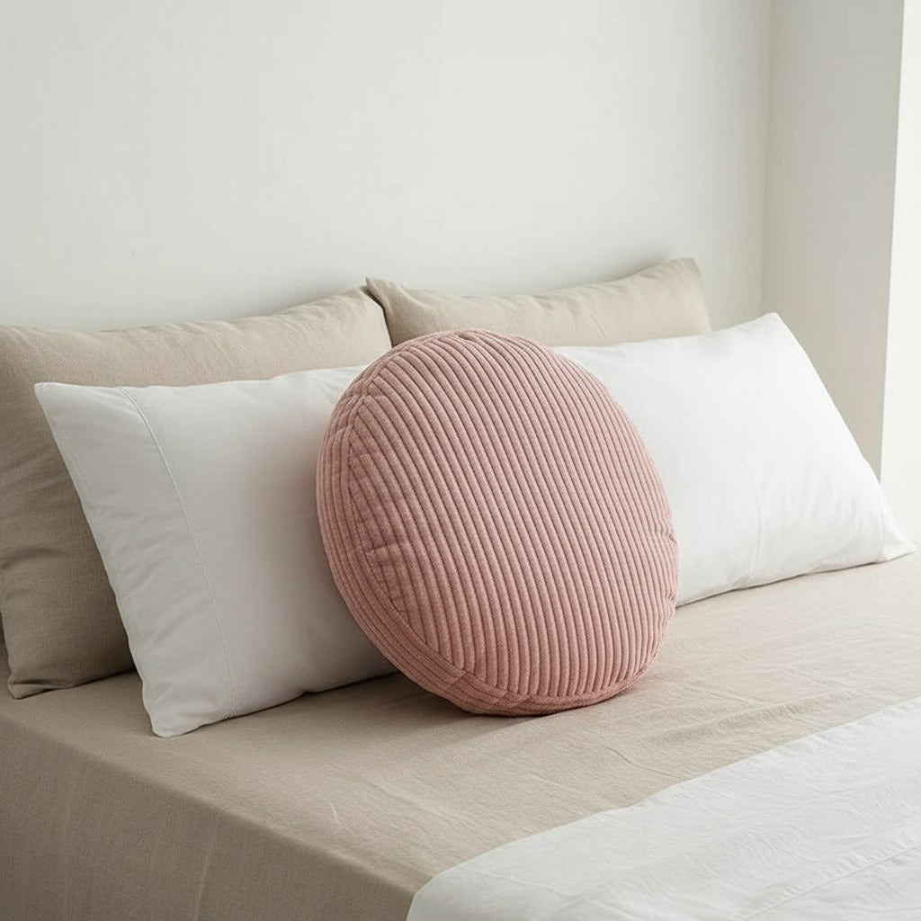 Coussin rond en velours côtelé rose sur un lit