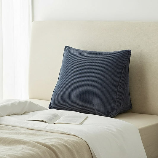 Coussin triangulaire bleu marine calé contre la tête de lit pour lire