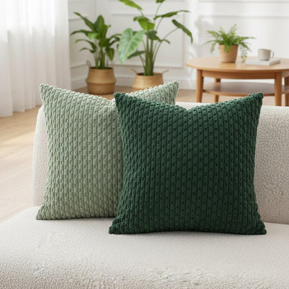 Coussins vert sauge et vert bouteille sur un canapé en bouclette crème