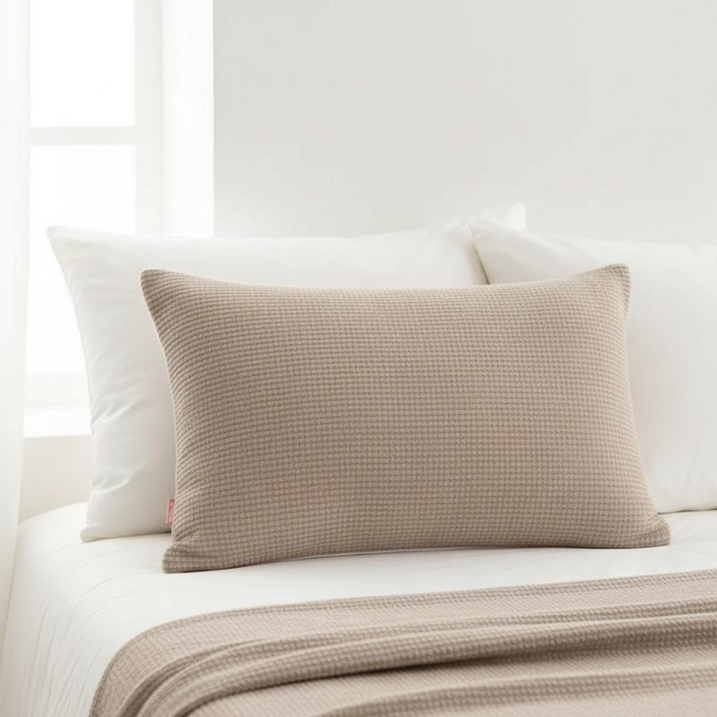 Coussin rectangulaire 50 x 70 cm taupe posé devant les oreillers blancs d'un lit