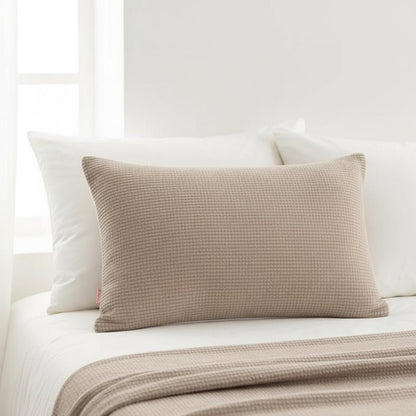 Coussin rectangulaire 50 x 70 cm taupe posé devant les oreillers blancs d'un lit