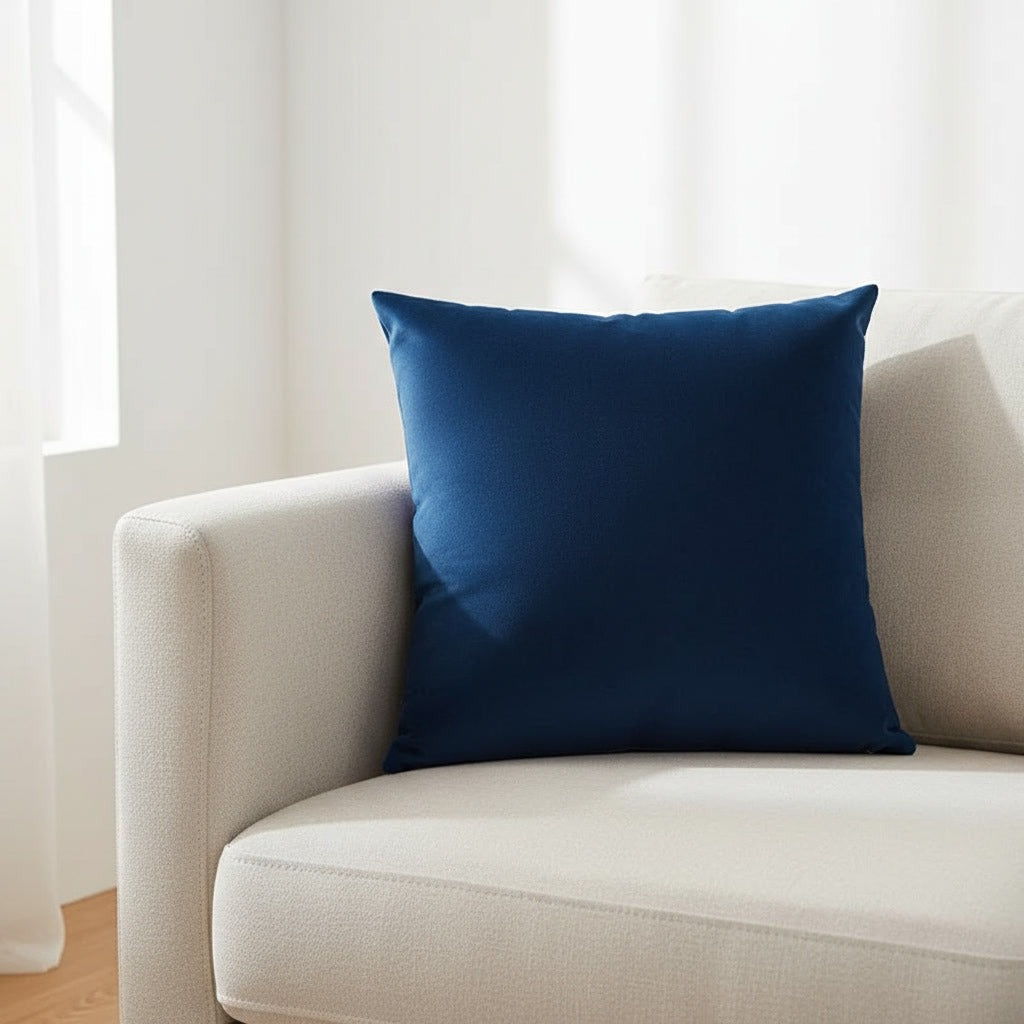Housse de coussin en velours bleu marine 45x45 cm posée sur un canapé en lin beige
