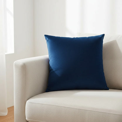 Housse de coussin en velours bleu marine 45x45 cm posée sur un canapé en lin beige