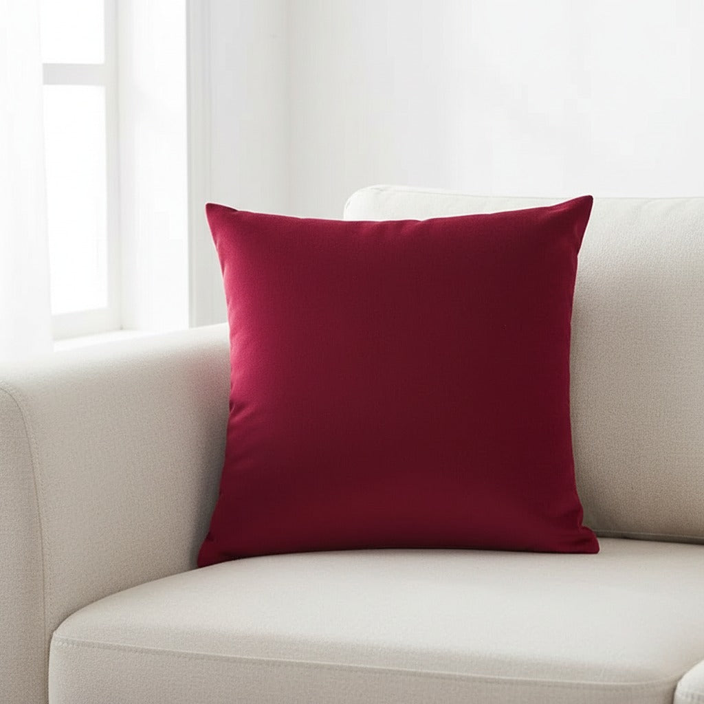 Housse de coussin en velours bordeaux 45x45 cm posée sur un canapé en lin beige
