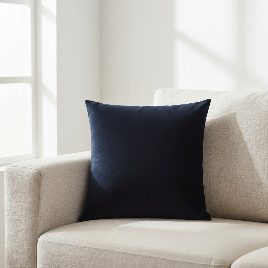 Housse de coussin en velours noir 45x45 cm posée sur un canapé en lin beige