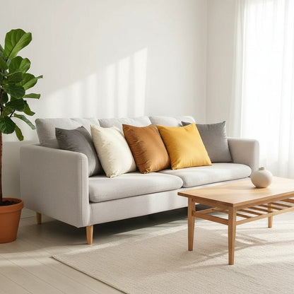 Housses de coussin en velours crème, orange et jaune moutarde sur un canapé gris dans un salon lumineux