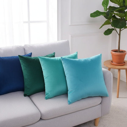 Housses de coussin en velours bleu marine, émeraude, turquoise et bleu ciel sur un canapé gris clair