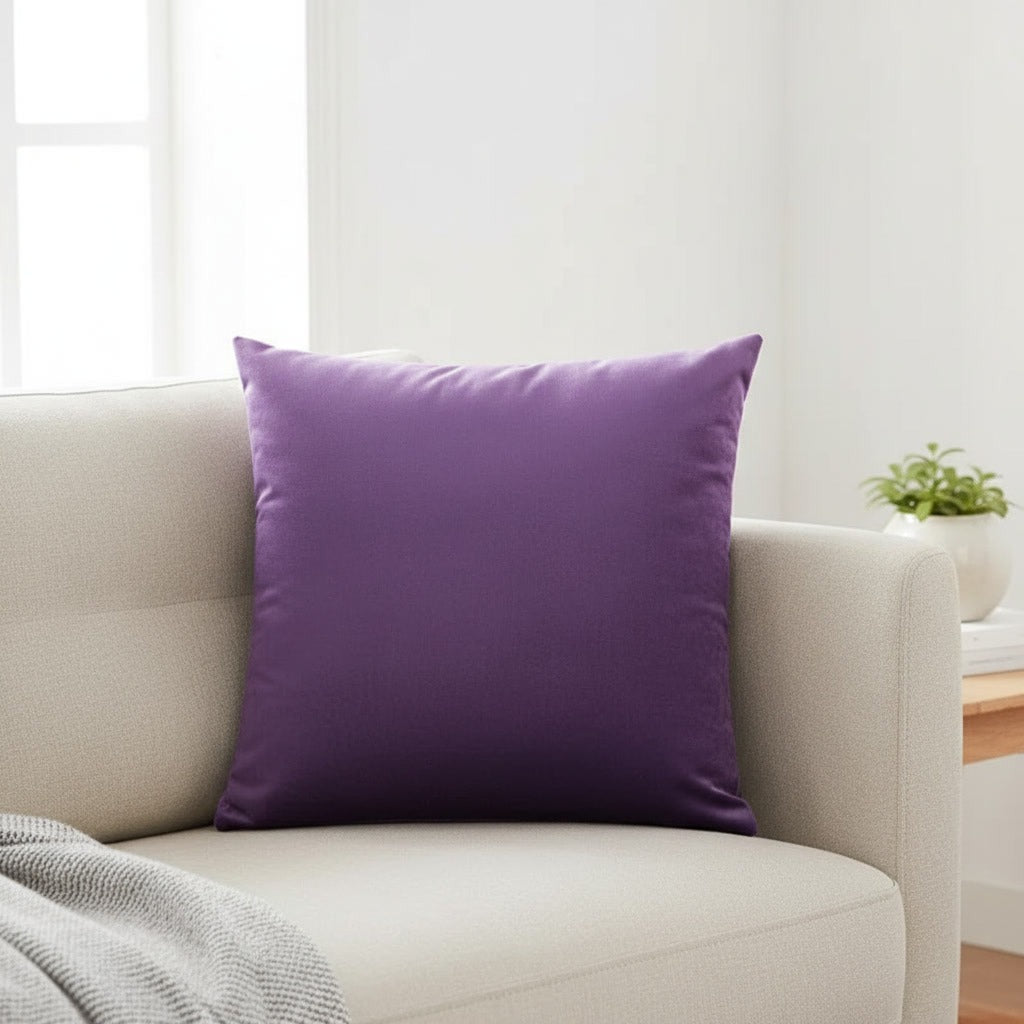 Housse de coussin en velours violet 45x45 cm posée sur un canapé en lin beige