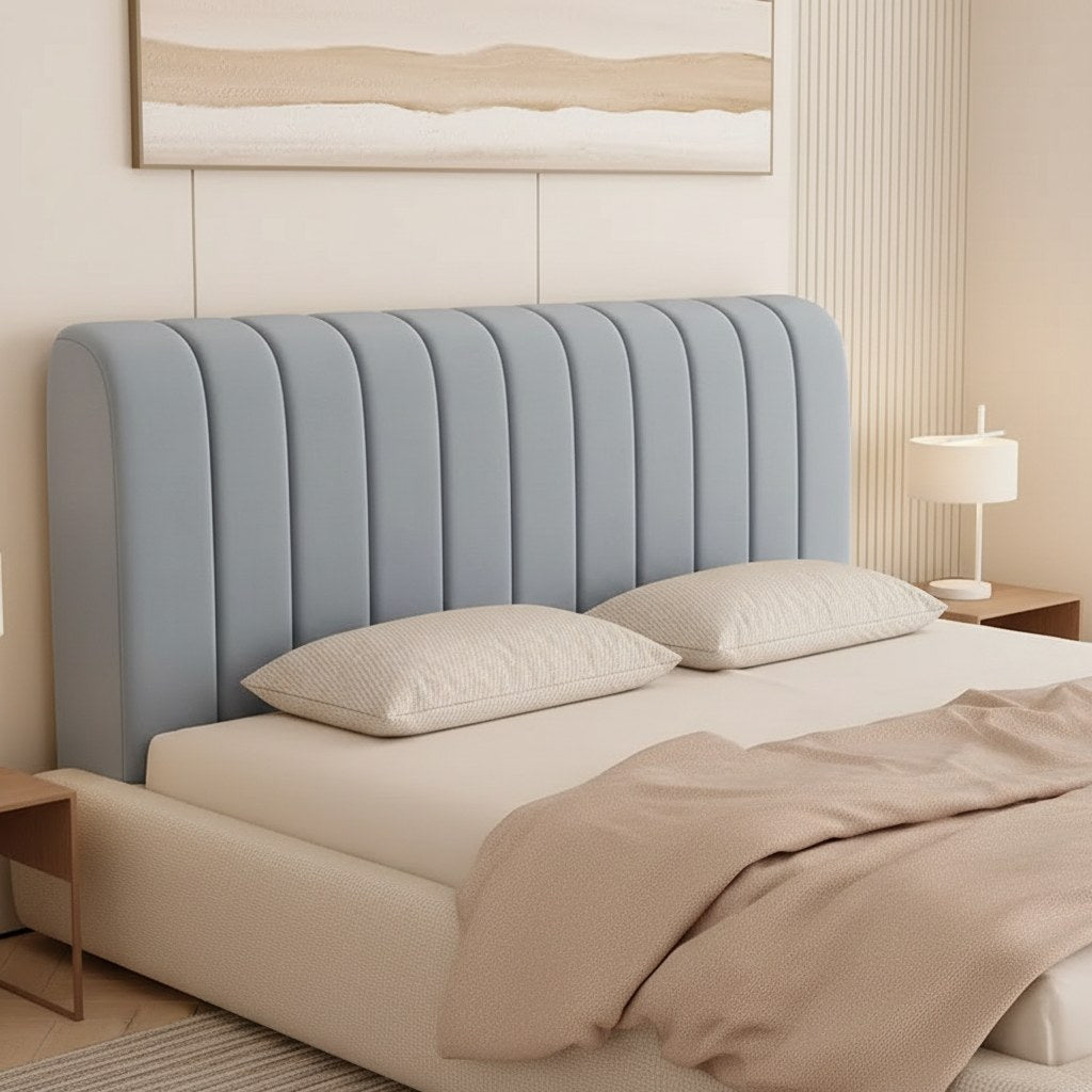Tête de lit habillée d'une housse extensible en velours gris bleu à matelassage vertical, dans une chambre claire