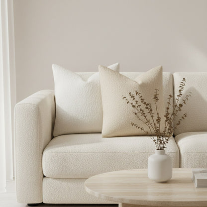 Housses de coussin bouclette blanche et beige sur un canapé crème