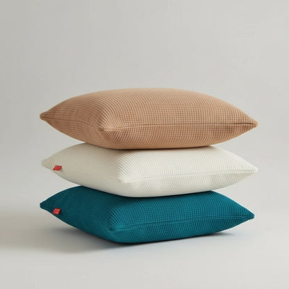 Trois coussins rectangulaires empilés, housses en maille texturée caramel, crème et bleu canard