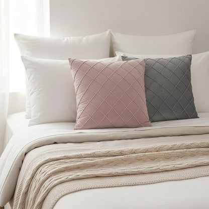 Housses de coussin en velours rose et gris à losanges plissés sur un lit