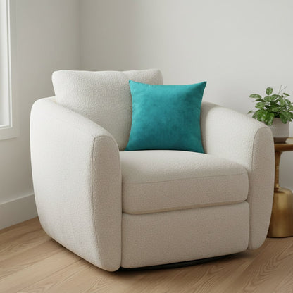 Petit coussin en velours bleu paon de 35 x 35 cm dans un fauteuil bouclette crème